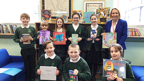 Helen hands books to children at a local school