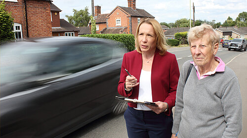 Helen Morgan and resident with vehicles speeding past